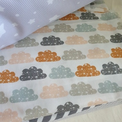 Tecidos com padrões de nuvens coloridas e estrelas brancas no fundo lilás