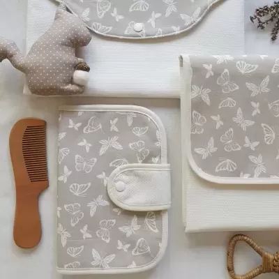 Conjunto de artigos para bebé com padrão de borboletas e acessórios em tons bege e branco