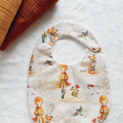 Babete branco com padrão do Principezinho e panos mostarda e terracota ao lado