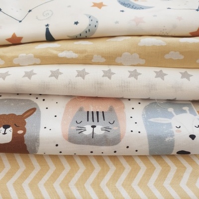 Pilha de tecidos coloridos com padrões de estrelas, nuvens e animais desenhados