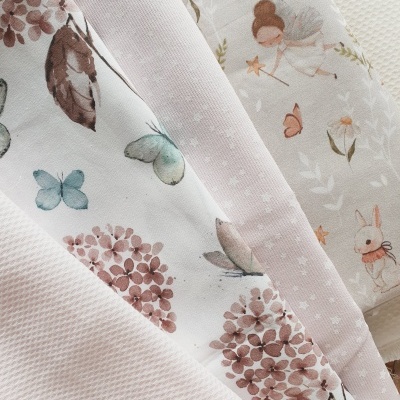 Tecidos infantis com flores, borboletas, fadas e coelhos em tons pastel