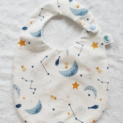 Babete branco com padrão de luas, estrelas e constelações.