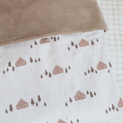manta de bebé castanha e branca com padrão de casinhas e árvores