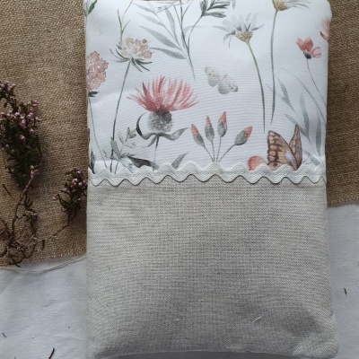 Almofada retangular cinza e branca com padrão floral e borboleta, detalhada com fita ondulada branca