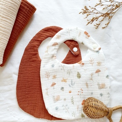 Dois babetes para bebé com padrões naturais e cores suaves