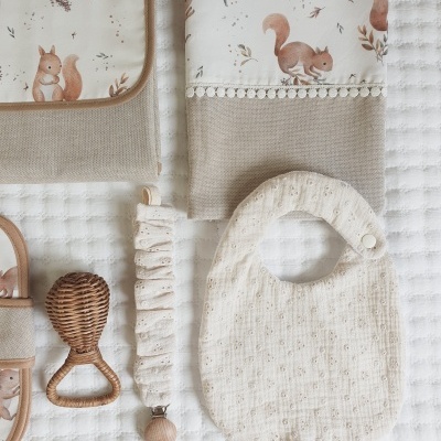 Toalhas de bebé com padrão de esquilos, babete creme e chocalho em rattan