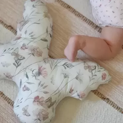 Almofada floral decorativa e braço de bebé num tapete