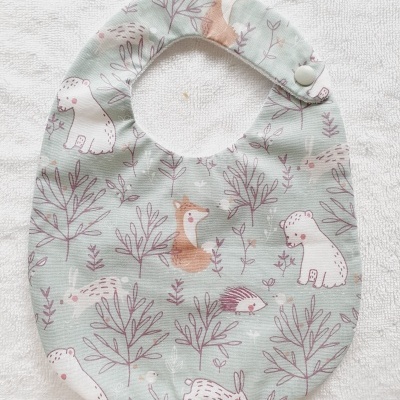 Babete para bebés com padrão de animais e plantas em tons pastel