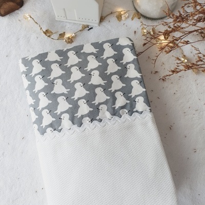 Fralda ou toalha com padrão de fantasmas sobre superfície branca decorada com luzes e ramos secos