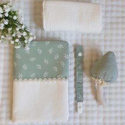 Conjunto de fralda, proteção, prendedor de chupeta e brinquedo sobre fundo branco acolchoado