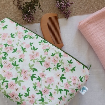 Bolsa de tecido com padrão floral rosa e verde junto com pente de madeira e tecido rosa