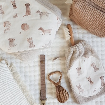 Artigos de bebé com padrão de cães sobre manta branca texturada