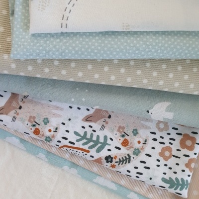 Tecidos variados com padrões de bolinhas, flores, folhas e pássaros em tons pastel