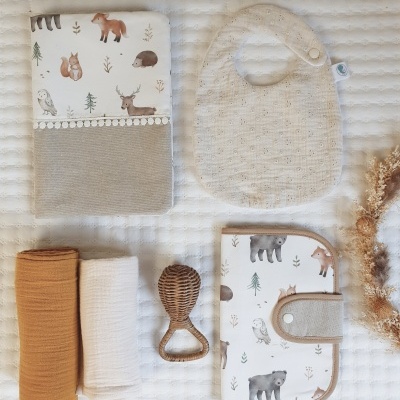Conjunto de produtos para bebé com capa, babete, mantas, chocalho e carteira com padrão de animais