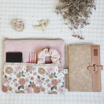 Necessaire floral com estojo rosa, canetas cor-de-rosa, scrunchie, telemóvel, agenda bege com detalhes castanhos 2024, raminho seco, ornamentos flor e pássaro