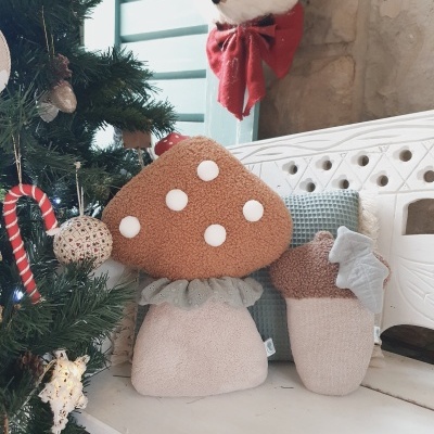 Brinquedos de pelúcia de cogumelos ao lado de árvore de Natal decorada