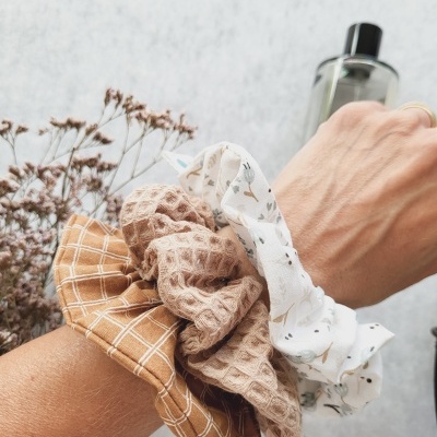 Três scrunchies de tecido coloridos no pulso com padrões diferentes