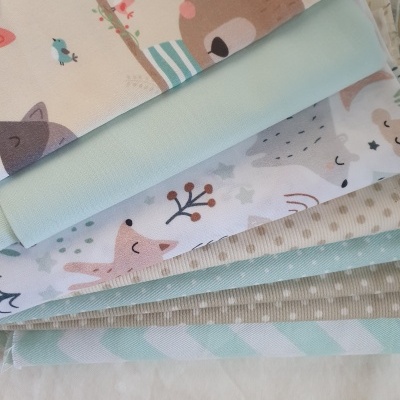 Tecidos infantis com estampas de animais e texturas diversas em tons pastel