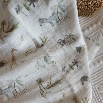 tecido branco com padrão de animais selvagens em tons suaves colocado sobre superfície têxtil branca estruturada e objeto de fibra natural