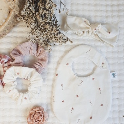 Acessórios para bebé com padrão floral rosa sobre superfície branca texturizada