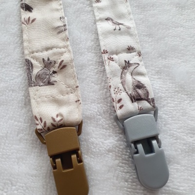 Cordões com presilhas plásticas e estampas de animais em tecido branco.