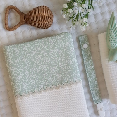 Conjunto para bebé com capa floral verde, faixa para chupeta, toalha branca e flores.