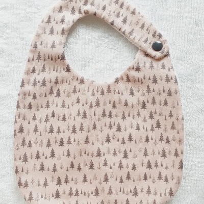 Babete bege com padrão de árvores castanhas e fecho de botão negro