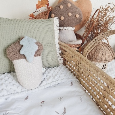 Berço de bebé com rede de palhinha, almofada verde e brinquedos de tecido em forma de cogumelos