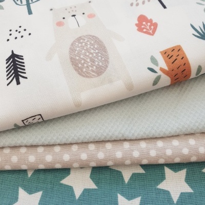 Quatro tecidos empilhados com diferentes padrões: ursos e árvores, textura quadriculada, bolinhas e estrelas.