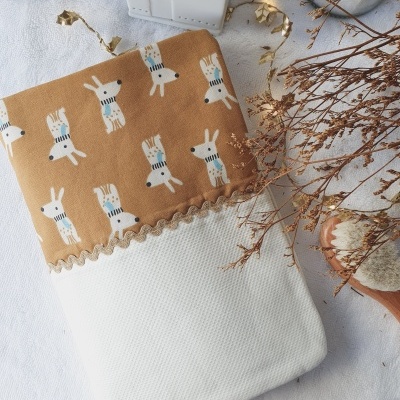 Toalha com padrão de cães e textura branca, com decoração seca ao lado