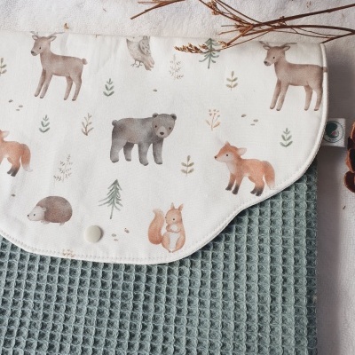 Manta ou capa com padrão de animais da floresta em tecido branco e base verde de textura waffle