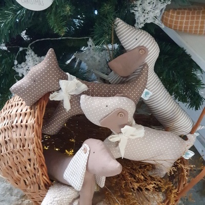 Cães de tecido decorativos com padrão riscado e bolinhas em cesto junto a decoração de Natal