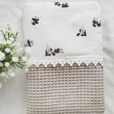 Toalha branca com estampa de pandas e tecido bege com padrão texturizado, com renda branca