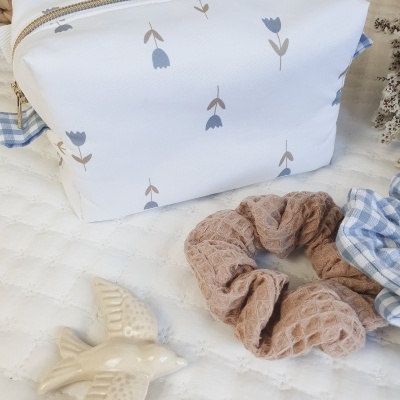 Necessaire branca com padrão floral e acessórios sobre superfície branca