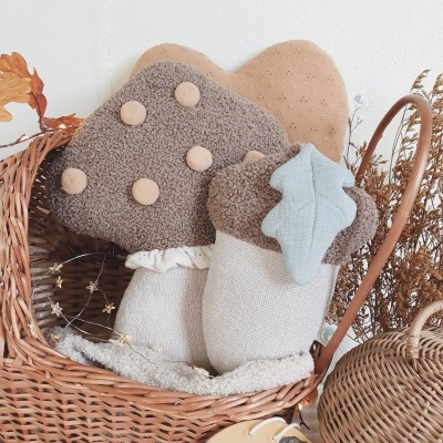 Almofadas decorativas em formato de cogumelo, carvalho e folha numa cesta de verga com flores secas