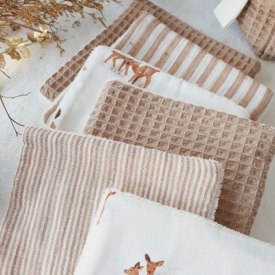 Toalhas bege e brancas com padrões e estampas de veados sobre superfície clara