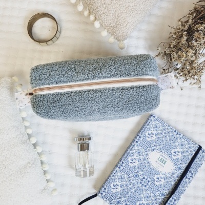 Necessaire azul felpudo com fecho de correr e caderno azul branco com texto LISE em superfície texturada branca