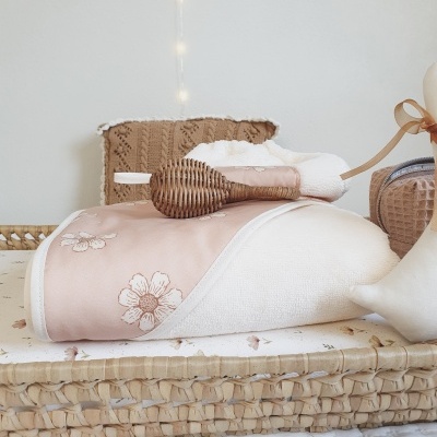 Cesta de vime com toalhas de banho floral, escova de madeira e manta castanha