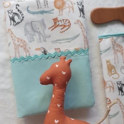 Capa com padrão de animais selvagens e peluche de girafa castanha com corações brancos