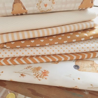 Pilha de tecidos com várias estampas e botões amarelos numa embalagem transparente