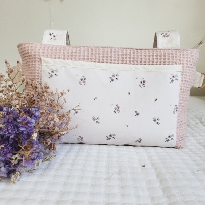 Almofada retangular rosa claro com padrão floral e ramo de flores secas roxas ao lado