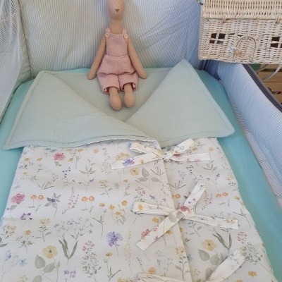 Berço com manta floral e peluche coelho rosa, cesta de vime na lateral