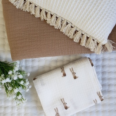 Tecidos dobrados sobre superfície branca acolchoada com pequenas flores ao lado