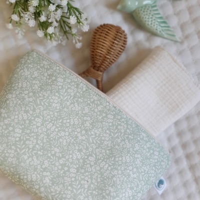 Bolsa de tecido floral com acessórios e decorações sobre superfície acolchoada