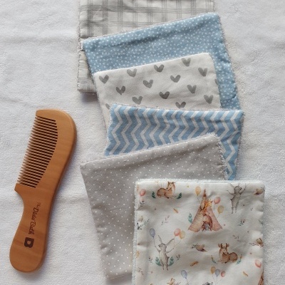 Paninhos de tecido com diversos padrões e pente de madeira numa toalha branca