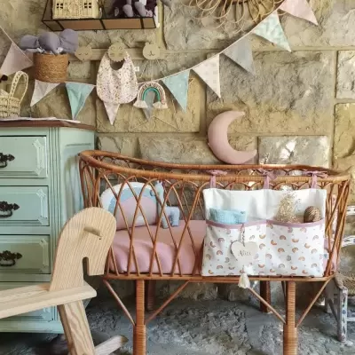 Berço de vime com decoração pastel e parede de pedra