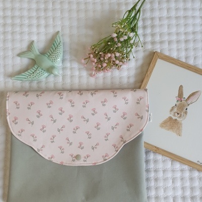 Bolsa cinza com aba rosa estampada, flores cor de rosa, ramo de flores, figura de pássaro verde e quadro com coelho.