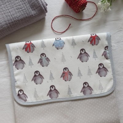 Toalha com estampado de pinguins em fundo branco e tecido bege com bolinhas brancas