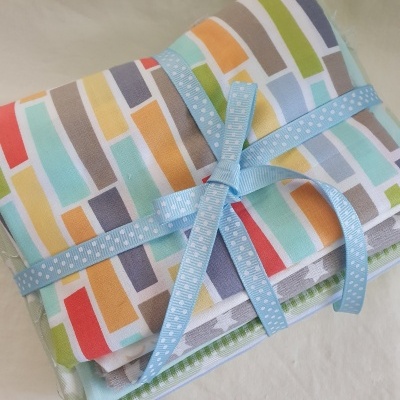 Conjunto de tecidos coloridos com padrão de retângulos e fita azul clara com pontos brancos