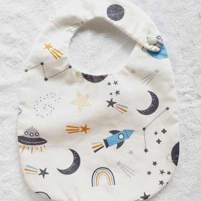 Babete de bebé com padrão espacial colorido em fundo branco
